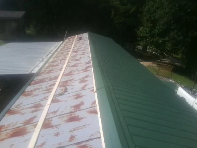 Old rusted panels beside newly installed green metal roofing — Wind Damage Roof Repair by Roofing Brothers in Bainbridge