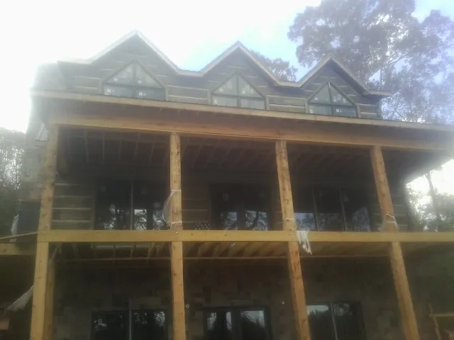 Dormers and porch framing on a large log home under construction — Roof Coating work by our crew in Bainbridge